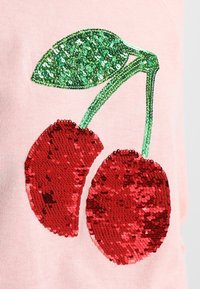 Rosa tyg med en paljettdesign av två röda körsbär med gröna blad, vilket tillför textur och visuellt intresse till plagget.