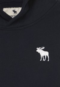 Felpa blu navy con un design a ricamo bianco di un alce sul petto, con una texture morbida e uno stile classico a pullover.