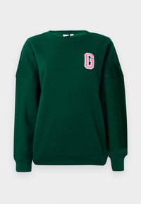 Sweatshirt vert, en mélange de coton, col rond, épaules décalées, avec une lettre "G" brodée en rose sur la poitrine gauche. Coupe classique.