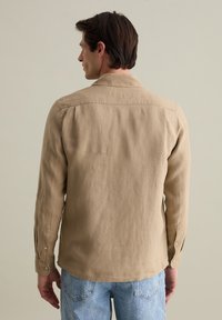 Lichtbruin, langarm shirt van linnen met een relaxed fit. Bevat een puntkraag en knoopmanchetten, met een gladde, licht gestructureerde oppervlakte.