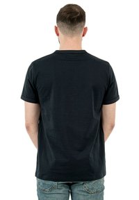 T-shirt nera in cotone con maniche corte, scollatura rotonda e una texture liscia, vista da dietro su uno sfondo bianco.