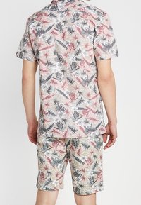 Conjunto de camiseta de manga corta y pantalones cortos con un estampado de flores y hojas en colores pastel, hecho de tela ligera con un corte relajado.