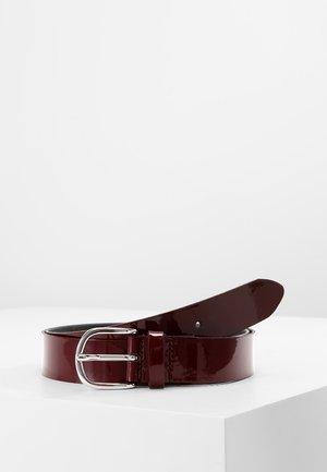 Dunkelroter glänzender Ledergürtel mit silberner Doppelstiftschnalle, aufgerollt und auf einer weißen Oberfläche dargestellt.