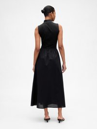 Abito nero senza maniche con collo alto, vita aderente e gonna fluida. Realizzato in tessuto leggero con una texture liscia.