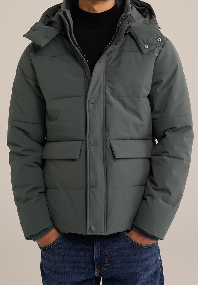 Grå puffjacka med huva, med tryckknappar, två framfickor och ribbade ärmslut, designad med kviltade sektioner för isolering.