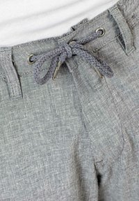 Light gray linen pants with a woven drawstring waistband and metallic eyelets. The fabric has a textured finish with a subtle pattern.