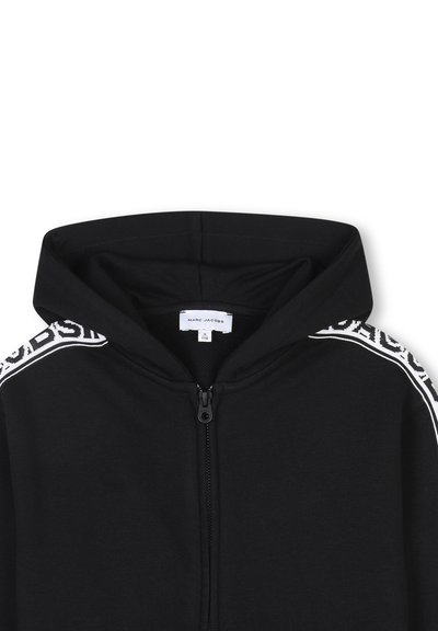 Sweat à zip noir avec une texture douce, doté d'une capuche doublée et de bandes de logo blanches contrastantes le long des épaules.
