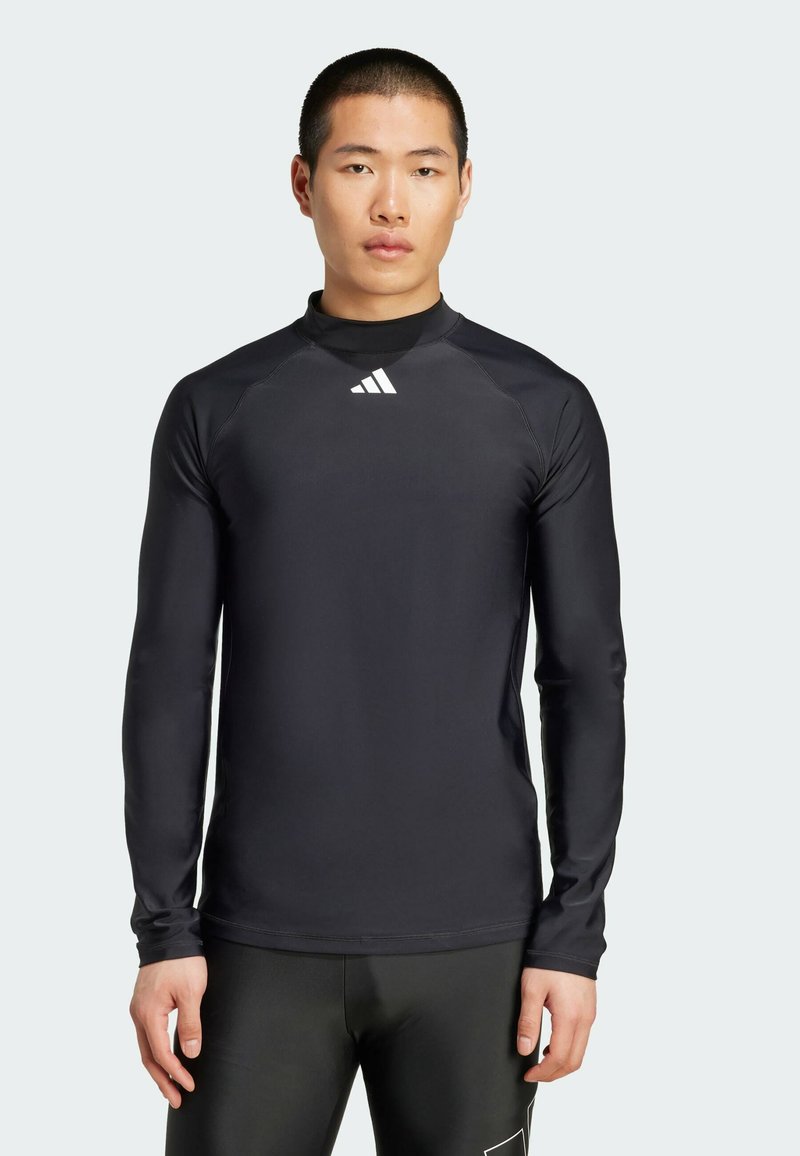 Zwart sportshirt met lange mouwen van synthetisch materiaal, met een ribbelkraag en een klein wit logo op de borst.