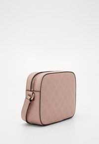Světle růžová obdélníková crossbody taška s embosovanými geometrickými vzory a zlatým zipem, zobrazená z mírného úhlu na bílém pozadí.