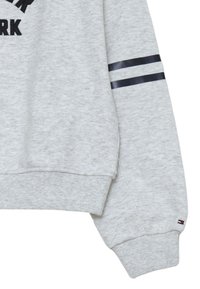 Felpa grigia con polsini a costine, con accenti a righe nere e bianche sulle maniche e la scritta "NEW YORK" ricamata in nero.