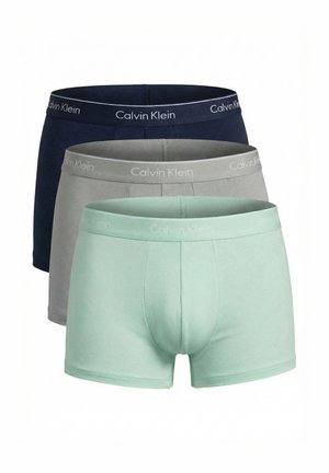 Tre paia di boxer da uomo Calvin Klein impilati uno davanti all'altro in verde menta, grigio e blu navy, ciascuno con elastico in vita con il marchio.