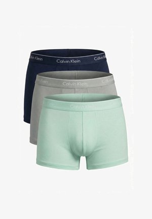 Trois paires de boxers pour hommes Calvin Klein empilées de face à dos en vert menthe, gris et bleu marine, chacune avec une ceinture élastique marquée.