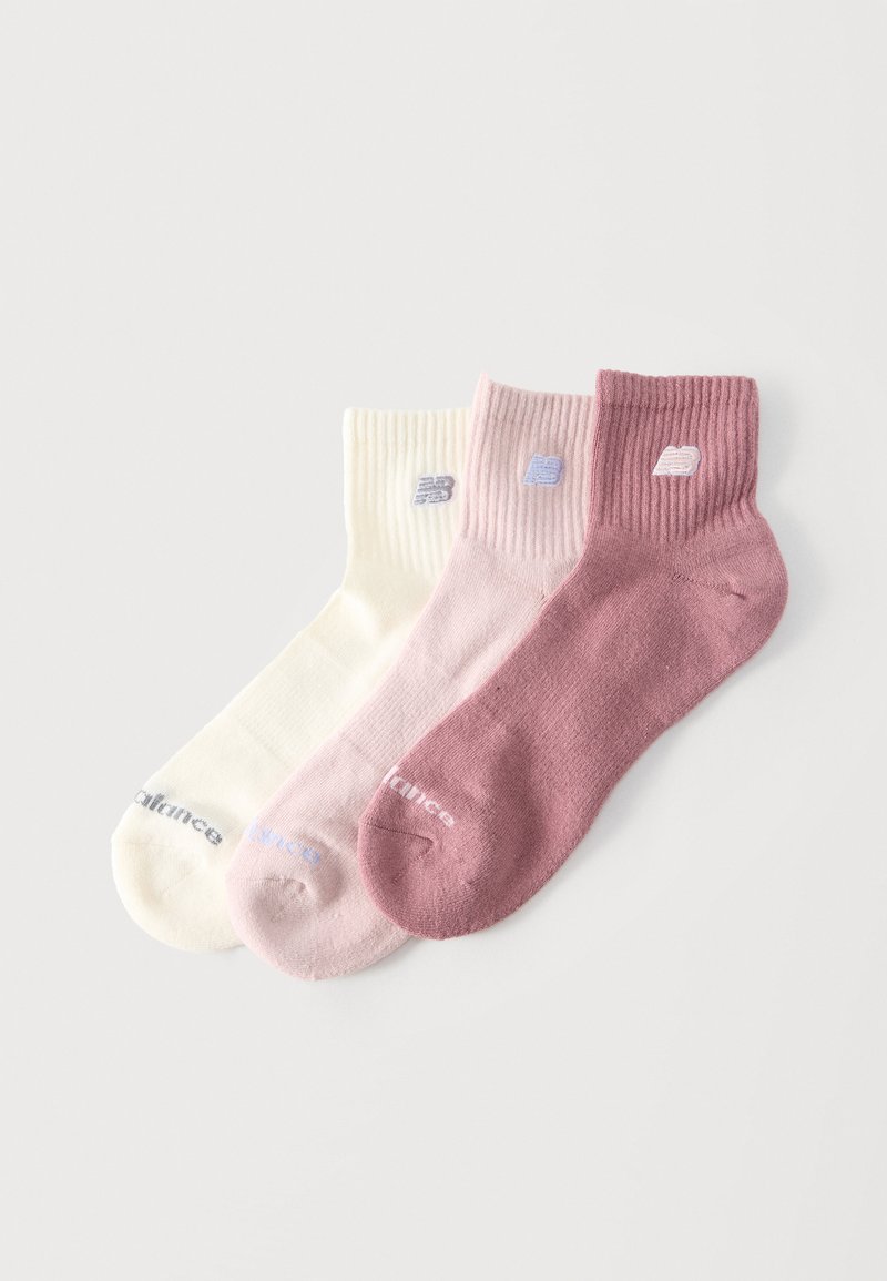 Trois chaussettes basses en crème, rose clair et mauve, chacune avec une bordure côtelée et un petit logo brodé près du haut.