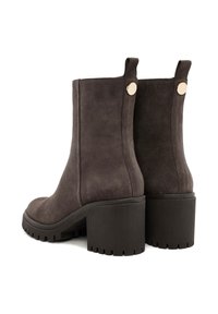 Dark gray suede ankle boots featuring a chunky, ridged black heel and gold accent buttons on the side. Smooth texture with a minimalist design.