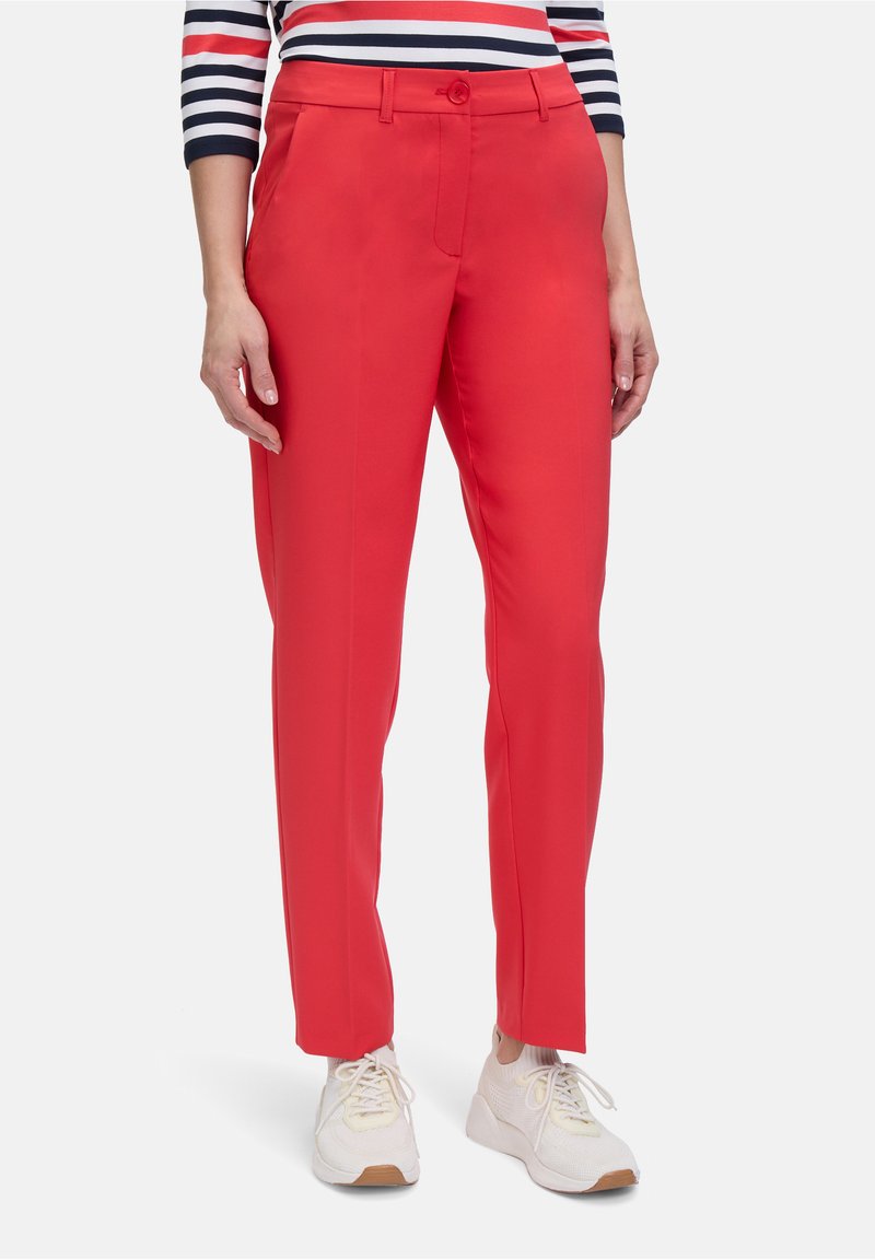 Czerwone spodnie o dopasowanym kroju, z gładką teksturą, z kieszeniami z przodu i zapięciem na jeden guzik. W zestawie z białymi trampkami.