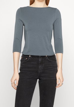 Gray, fitted top with three-quarter sleeves and a boat neckline, paired with high-waisted, dark denim jeans. Smooth texture, minimal design.