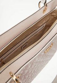 Borsa a tracolla trapuntata rosa con hardware dorato, dotata di chiusura con zip e numerose tasche interne foderate in tessuto beige con logo.