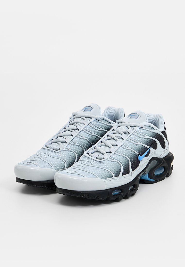 Baskets de sport gris clair avec des accents gris foncé, tige en mesh et détails bleus. Présentent une pointe arrondie et un amorti d'air visible dans la semelle.