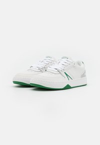 Valged sneakers roheliste aksentidega. Valmistatud siledast nahast, lame tald, kootud esiosa, perforatsioonidega varvas ja kontrastsed külgtriibud.