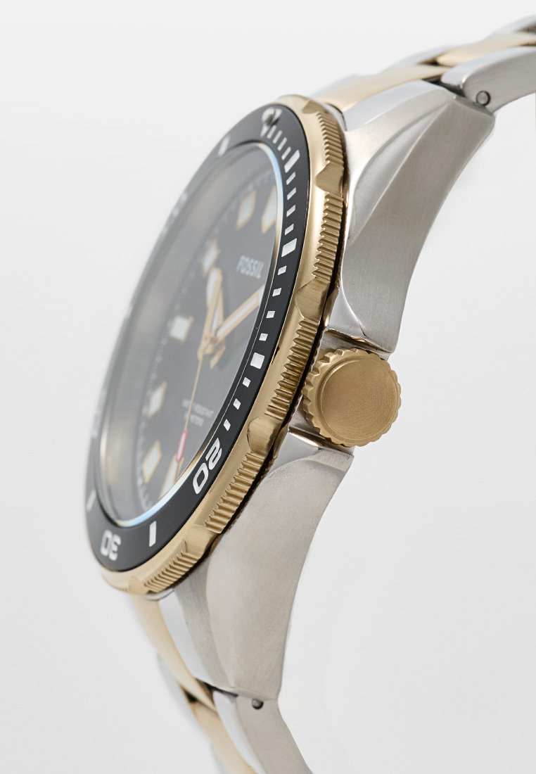 Orologio da uomo con quadrante nero, dettagli dorati, bracciale in acciaio inossidabile, lunetta rotante dorata e corona laterale texturizzata per la regolazione.