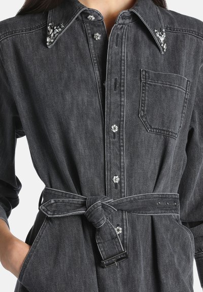 Robe chemise en jean gris foncé avec boutons en strass floraux, col orné, poche poitrine, ceinture à la taille nouée devant et poches latérales.