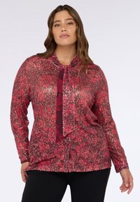Top a maniche lunghe con un motivo floreale in paillettes in rosa e bordeaux, con scollo a cravatta e tessuto strutturato.