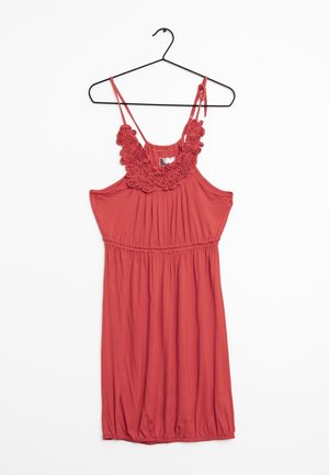 Korallenfarbenes ärmelloses Kleid mit elastischem Bund, verstellbaren Schulterriemen und floralen Crochet-Details am Ausschnitt, hängt an einem schwarzen Kleiderbügel.