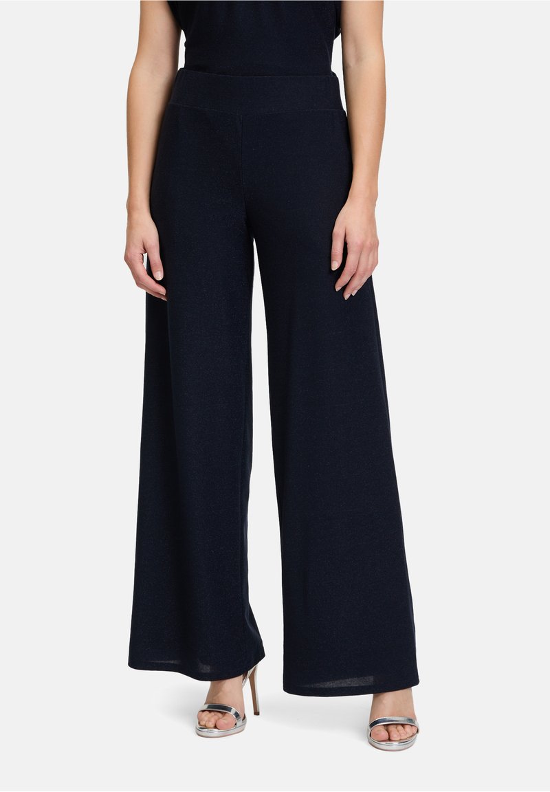 Weite Hosen aus navyblauem Stoff mit glatter Textur und hohem Bund. Kombiniert mit metallicfarbigen Absatzsandalen.