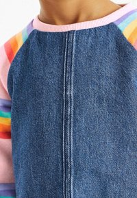 Denim top met een blauwe lijf, een roze ribbels halslijn en meerkleurige gestreepte mouwen. Bevat een verticale naad in het midden van de voorkant.