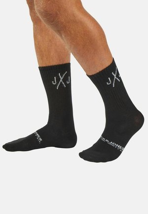 Black cotton socks with ribbed texture, featuring white logo and lettering on the upper side and printed text on the sole.