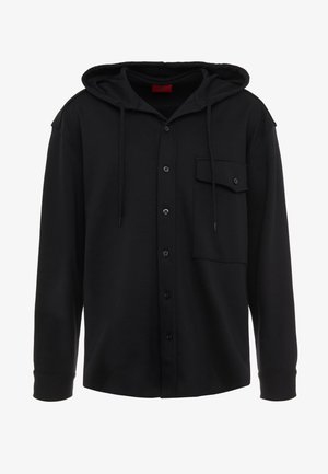 Sudadera negra con capucha, cierre de botones y un bolsillo en el pecho. Está hecha de una tela suave, con un corte relajado y mangas largas.