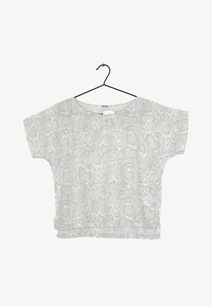 Kortærmet, løs hvid top med lysegrå slangeprint hængende på en sort bøjle mod hvid baggrund.