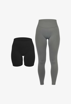 Frau trägt graue Leggings mit hoher Taille und passendes cropped Top, steht aufrecht mit locker hängenden Armen, trägt weiße Sneakers.