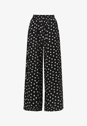 Wide-leg trousers made of soft fabric, featuring a black background with large white polka dots and an elastic waistband for comfort.