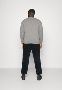 Grijze trui met een ronde hals, gecombineerd met marineblauwe fluwelen broek en zwarte enkellaarsjes; minimalistisch ontwerp, geen zichtbare patronen.