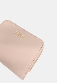 Cartera texturizada rosa con cierre de cremallera y el logo dorado "LIU JO". Presenta bordes curvados y costuras visibles a lo largo de las costuras.