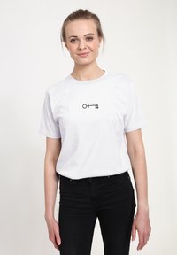 Hvid bomulds T-shirt med korte �ærmer, der har et sort nøgledesign og et kameraikon trykt på midten af brystet.