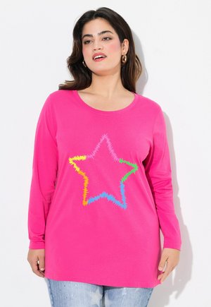 T-shirt à manches longues rose avec un motif d'étoiles multicolores dans un design texturé en zigzag, associé à un denim bleu clair à motif d'étoiles.