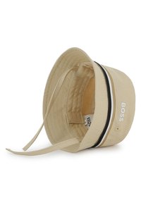 Μπεζ καπέλο τύπου κάπα με μαύρη και λευκή ριγέ ταινία, που διαθέτει λογότυπο της μάρκας. Κατασκευασμένο από υφή υφάσματος με ασφαλή λουρί πηγουνιού.