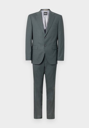 Costum gri închis format dintr-un sacou croitorit cu două nasturi și pantaloni asortați. Materialul este neted, cu un luciu subtil.