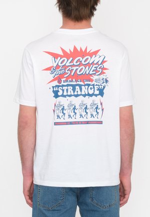 Camiseta de algodón blanca con un colorido estampado gráfico en la parte posterior que incluye el texto "Volcom & The Stones", diseños de esqueletos y acentos geométricos.