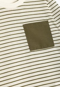 Gestreept T-shirt in crème en olijfgroen, met smalle horizontale strepen en een borstzak van stevig olijfkleurig stof.