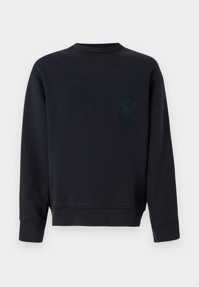 Black long-sleeve crewneck sweatshirt with ribbed cuffs and hem, featuring a small embossed logo patch on the left chest.