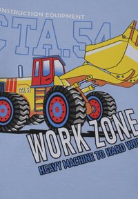 Ilustracja żółto-czerwonego ciężarówki załadunkowej z dużymi czarnymi oponami, na jasnoniebieskim tle. Tekst brzmi "STREFA ROBÓT" dużymi białymi literami.