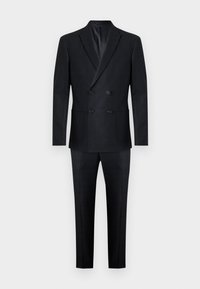 Traje de color azul marino de doble botonadura con una textura suave. Presenta dos bolsillos frontales y botones negros en la chaqueta, corte entallado y pantalones rectos.