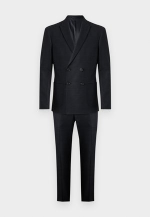 Traje de color azul marino de doble botonadura con una textura suave. Presenta dos bolsillos frontales y botones negros en la chaqueta, corte entallado y pantalones rectos.