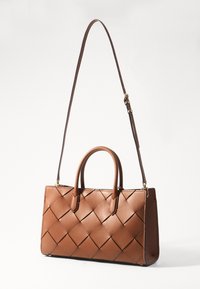 Bolso de mano de cuero marrón con diseño trenzado, dos asas superiores y correa de hombro desmontable. Textura suave y forma rectangular estructurada.