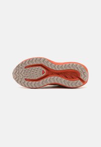 Skosåle med teksturert design og gummisåle, hovedsakelig lys grå med oransje detaljer langs kantene og i midten.