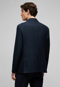 Marineblazer aus strukturiertem Stoff, mit einem Schlitz, geschlitzten Revers und Knopfdetails an den Manschetten. Die Rückansicht zeigt eine klare Silhouette.