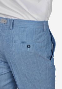 Lichtblauwe broek gemaakt van gestructureerde stof, voorzien van een zij-pocket, een achterzak met een knoop en een platte voorkant.
